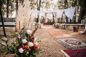 Guests can gather around the seating area with benches and tables, surrounded by lush greenery and vibrant flowers.