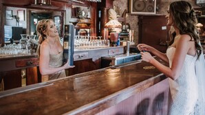 Un espace bar avec un comptoir en bois, des verres et une horloge.