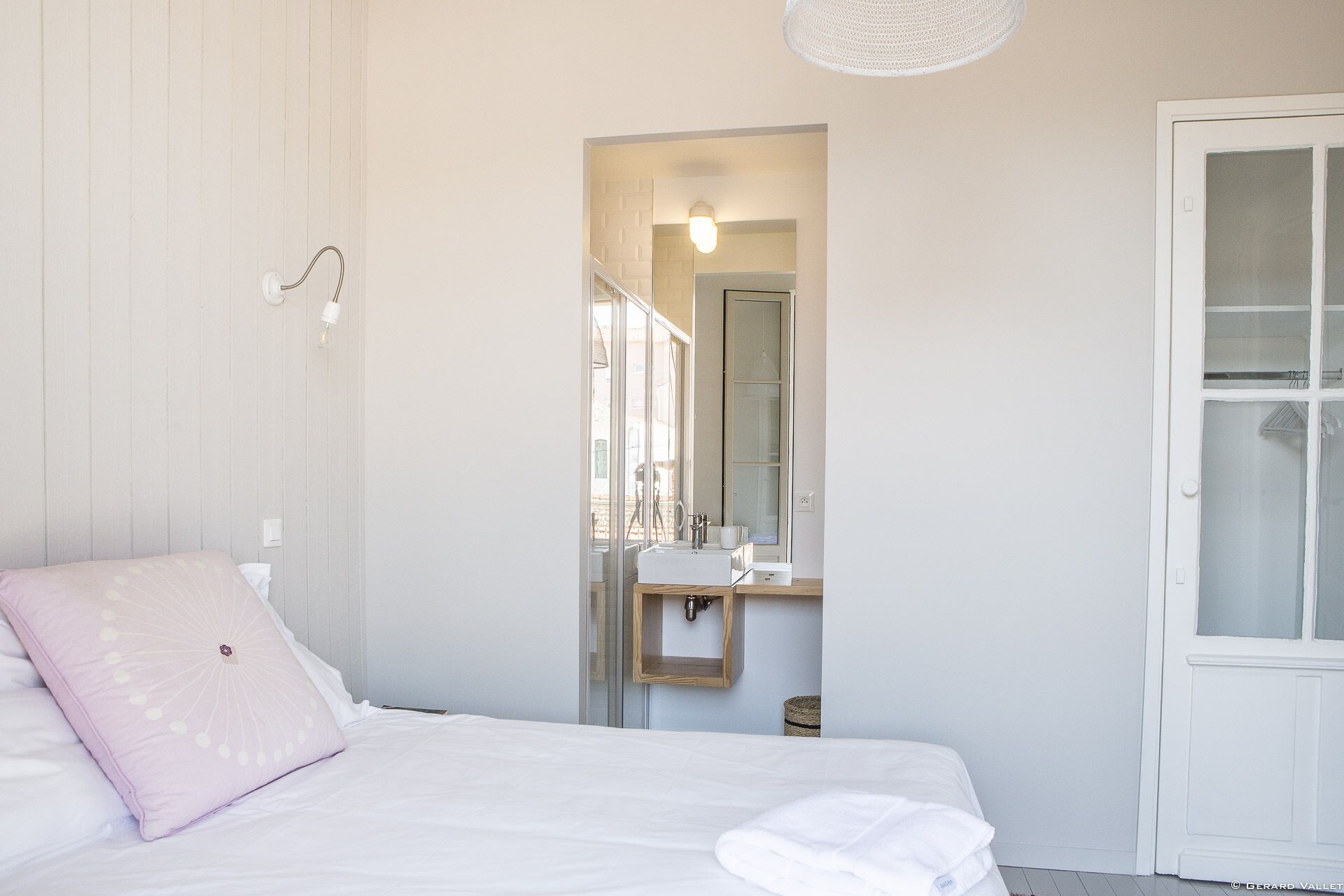 Un dormitorio con cama, lámpara de noche, ventana y puerta.