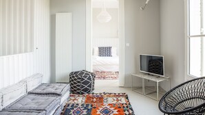 Ett modernt vardagsrum med en soffa, en mönstrad matta, en tv på ett TV-bord och en fåtölj i rotting.