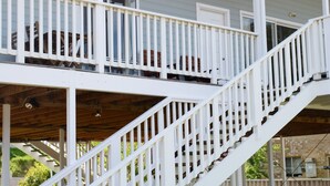 A white staircase leading to a covered outdoor area with a wooden deck.