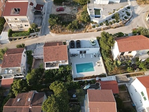 Vista aérea de um bairro residencial com várias casas, uma piscina e uma área de estacionamento.