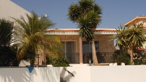 Ein Gebäude mit weißer Fassade, einem Ziegeldach und einer Treppe, die zu einem Balkon führt.