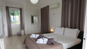 Ein Hotelzimmer mit Bett, Kleiderschrank, einem fenster mit Vorhängen, einer Klimaanlage und einem Nachttisch mit Lampe.
