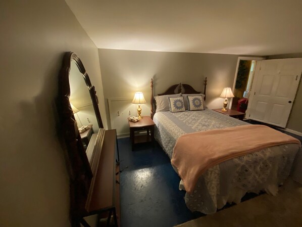 A bedroom with a bed, bedside tables, a mirror, and a door.