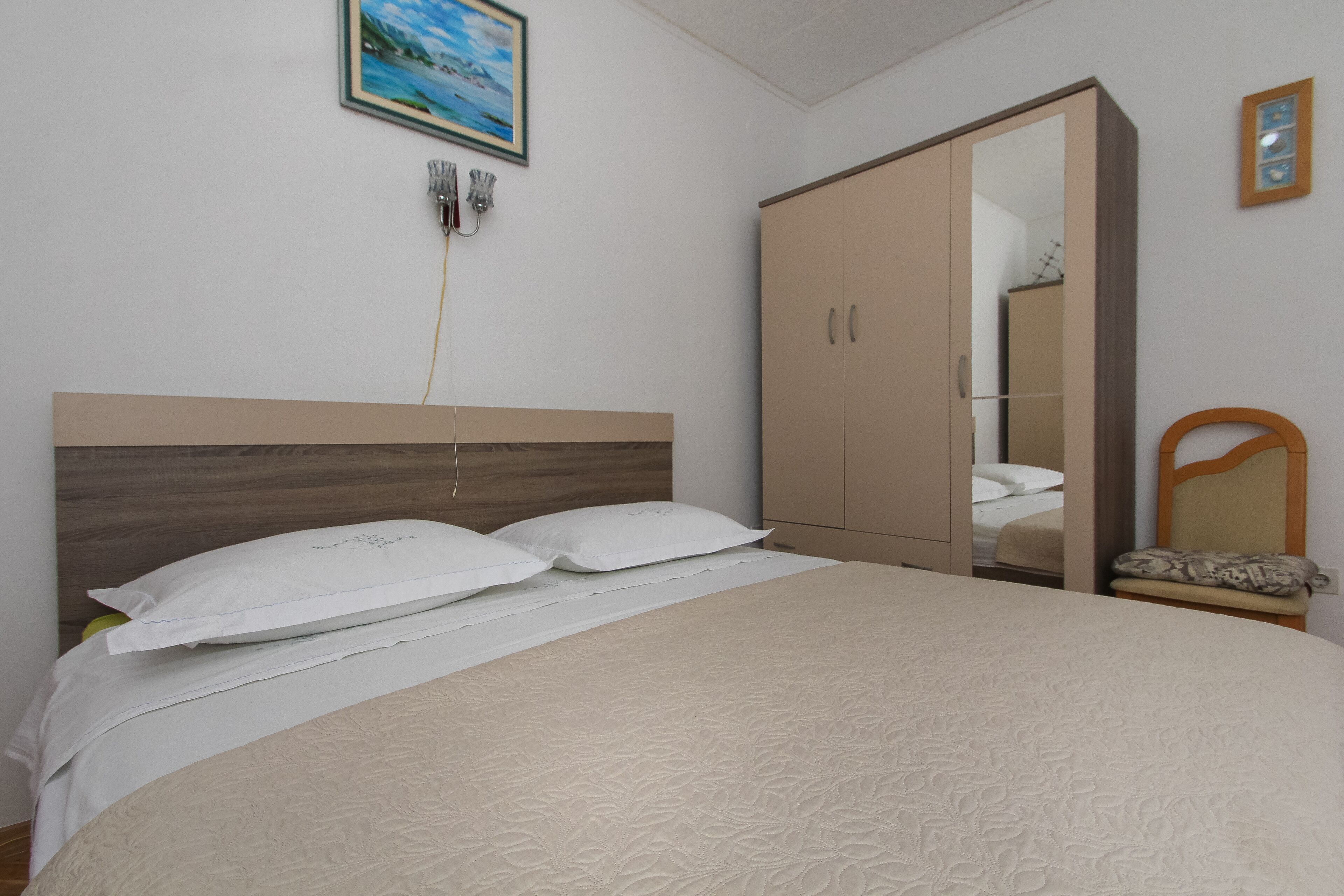 Une chambre à coucher avec un lit, une armoire, une chaise et un tableau au mur.
