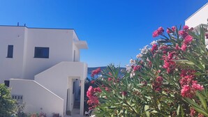 A modern white building with a flat roof, a staircase leading to the entrance, and a clear blue sky. - House with a unique view of the sea, islands in a quite position, EV-ready (Kaštel Sućurac)