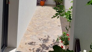 A narrow outdoor corridor with a tiled floor, potted plants, and a view of the sea. - House with a unique view of the sea, islands in a quite position, EV-ready (Kaštel Sućurac)