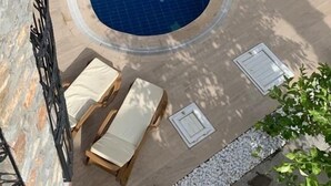 Una piscina con sillones de descanso y un muro de piedra.