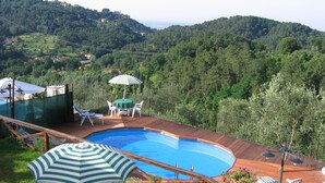 A pool area with a wooden deck, a table with chairs, and an umbrella.