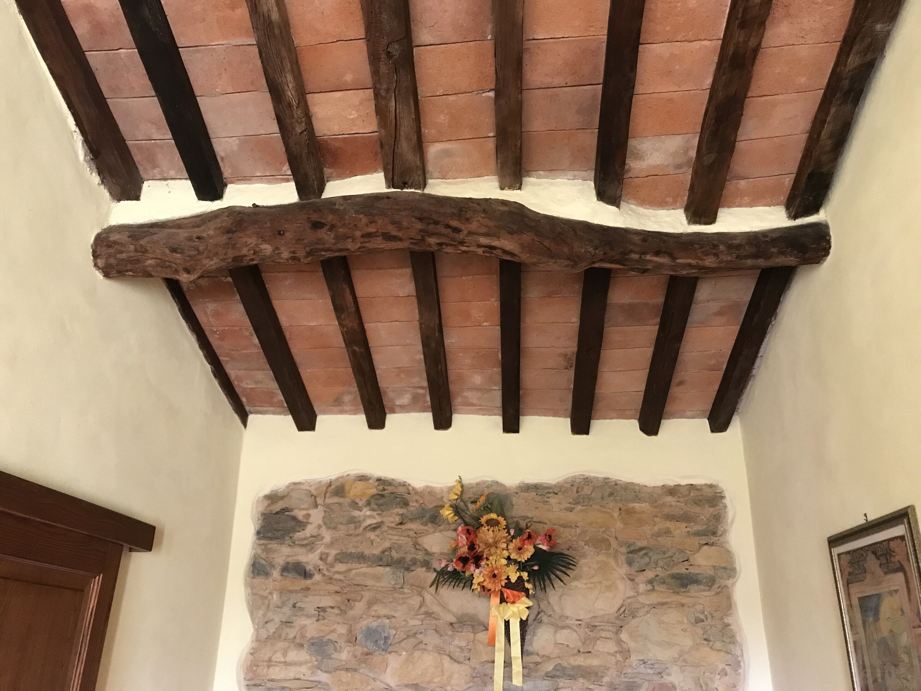 A stone wall with a wooden beam ceiling and a floral arrangement.