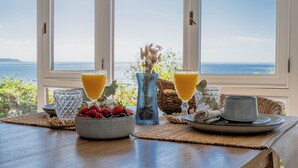 Ein Frühstückstisch mit einer Schale Erdbeeren, zwei Orangensaftgläsern, einer Vase mit Trockenblumen und einem Teller mit einer Tasse.