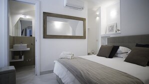 A bedroom with a bed, a bedside table, a mirror, a wall-mounted air conditioner, and a bathroom with a sink and towel rack. - Villa Mira: An elegant and welcoming three-story villa located in the center of Sant'Agnello, with Free WI-FI. (Sant'Agnello)