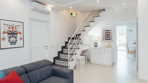 A modern living room with a grey sofa, a staircase with white railings, and a white cabinet. - Villa Mira: An elegant and welcoming three-story villa located in the center of Sant'Agnello, with Free WI-FI. (Sant'Agnello)