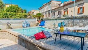 A poolside area with a lounge chair, a table with a bottle, and a small potted plant. - Villa Mira: An elegant and welcoming three-story villa located in the center of Sant'Agnello, with Free WI-FI. (Sant'Agnello)