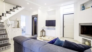 A modern living room with a grey sofa, a flat-screen TV, a fireplace, and a staircase with decorative railings. - Villa Mira: An elegant and welcoming three-story villa located in the center of Sant'Agnello, with Free WI-FI. (Sant'Agnello)
