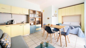 A compact hotel room with a kitchenette, a dining area, and a bed. - 1 bedroom gorgeous apartment in Oggebbio (VB) (Oggebbio (VB))
