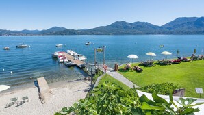 A lakeside view with boats docked, a bar, and a grassy area with umbrellas. - 1 bedroom gorgeous apartment in Oggebbio (VB) (Oggebbio (VB))