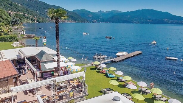 A lakeside resort with a dock, boats, and a grassy area with umbrellas. - 1 bedroom gorgeous apartment in Oggebbio (VB) (Oggebbio (VB))