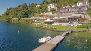 A waterfront property with a dock, lounge chairs, and a small boat. - 1 bedroom gorgeous apartment in Oggebbio (VB) (Oggebbio (VB))