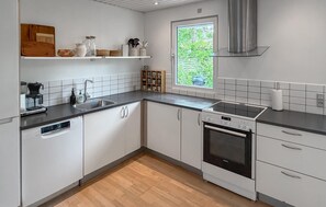 Una cucina moderna con mobili bianchi, un piano di lavoro nero, un forno integrato e una finestra vista verde.