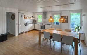Una cucina moderna con zona pranzo, pavimento in legno e illuminazione a sospensione.