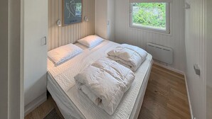 Een slaapkamer met een bed, een raam, een radiator en een ingelijst schilderij aan de muur.