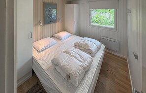 Una camera da letto con un letto, una finestra, un termosifone e un quadro appeso al muro.