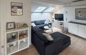 Un soggiorno moderno con un divano componibile, una televisione e un'area pranzo con tavolo e sedie.
