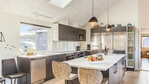 Una cocina moderna con una isla central, electrodomésticos de acero inoxidable y vistas al exterior.