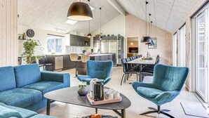 Una sala de estar moderna con sofás azules, una mesa de centro y un comedor con una mesa grande y sillas.
