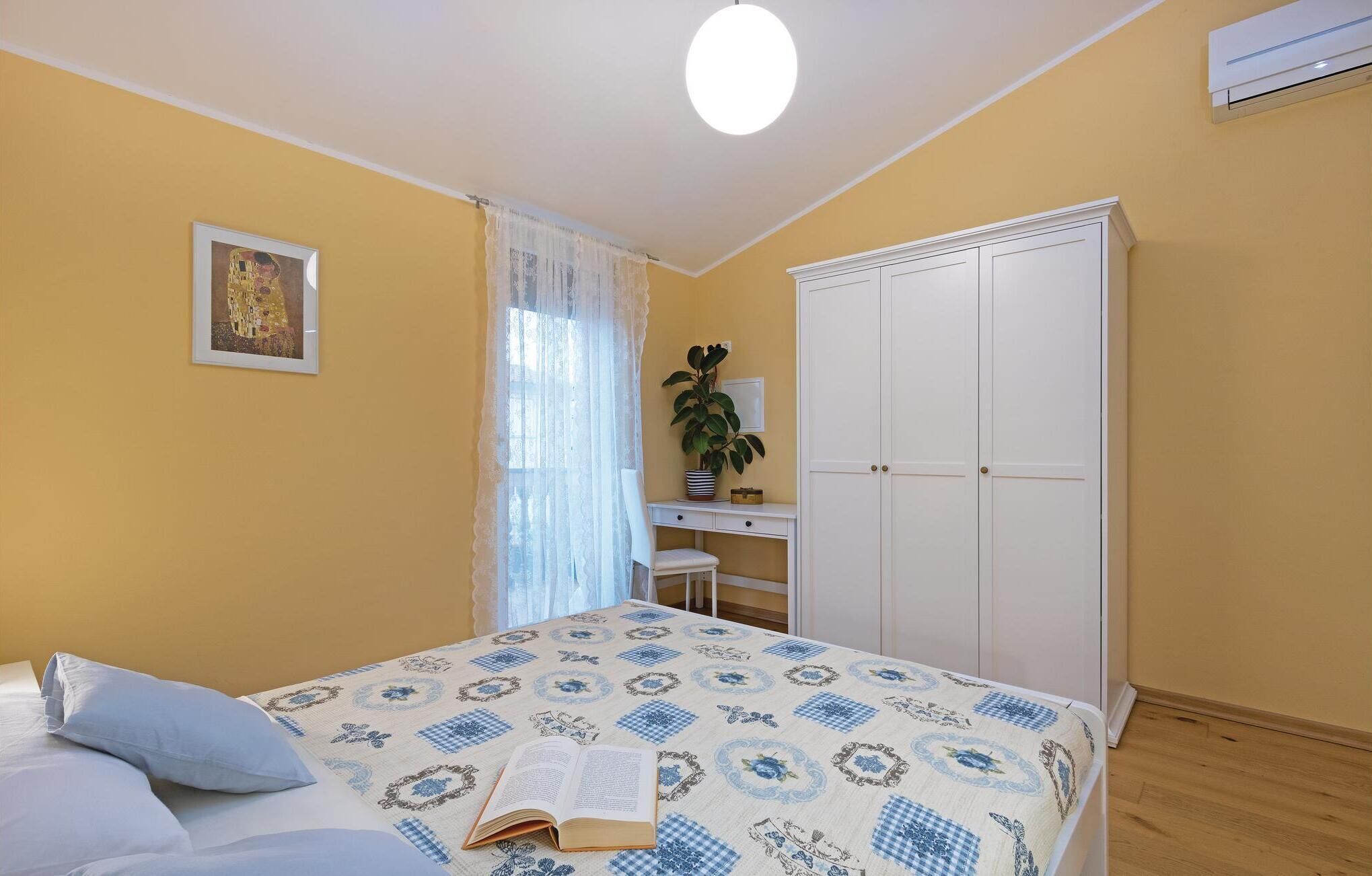 A bedroom with a bed, a desk, a wardrobe, and a window with curtains.