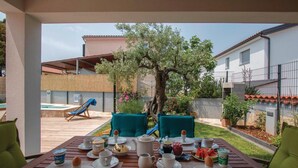 A patio table set for breakfast with a view of a tree and a slide in the background.