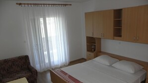 Un dormitorio con cama, armario de madera, una mesita y un sofá.