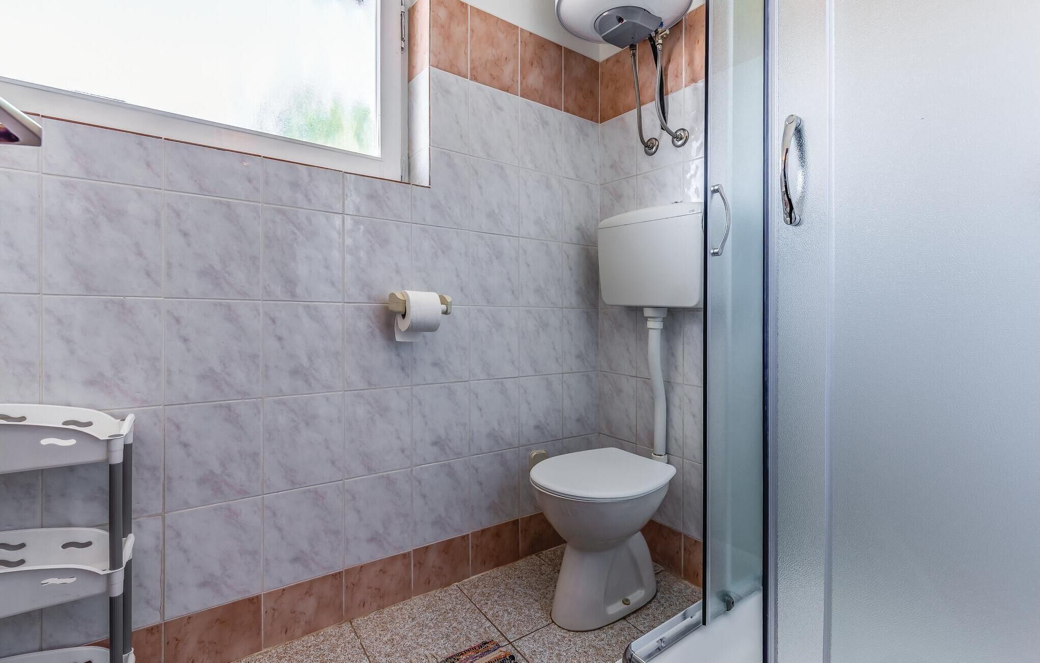 Un baño con inodoro, ducha y ventana.