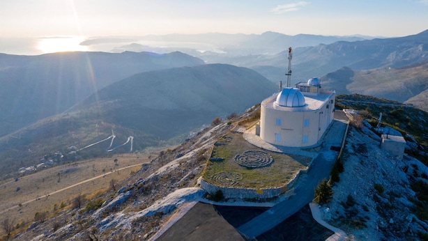 A circular building with a dome, surrounded by a stone wall and a spiral pattern on the ground, set against a mountainous backdrop. - Awesome home in Srinjine (Srinjine)