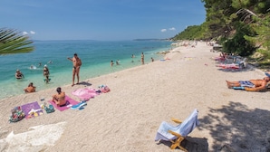 A beach with people sunbathing and swimming, clear blue water, and a sandy shore. - Awesome home in Srinjine (Srinjine)