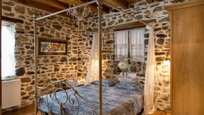 A stone-walled bedroom with a four-poster bed, a chandelier, and a wooden ceiling. - Luxury Traditional Stone House in Vrasna (Vrasna)