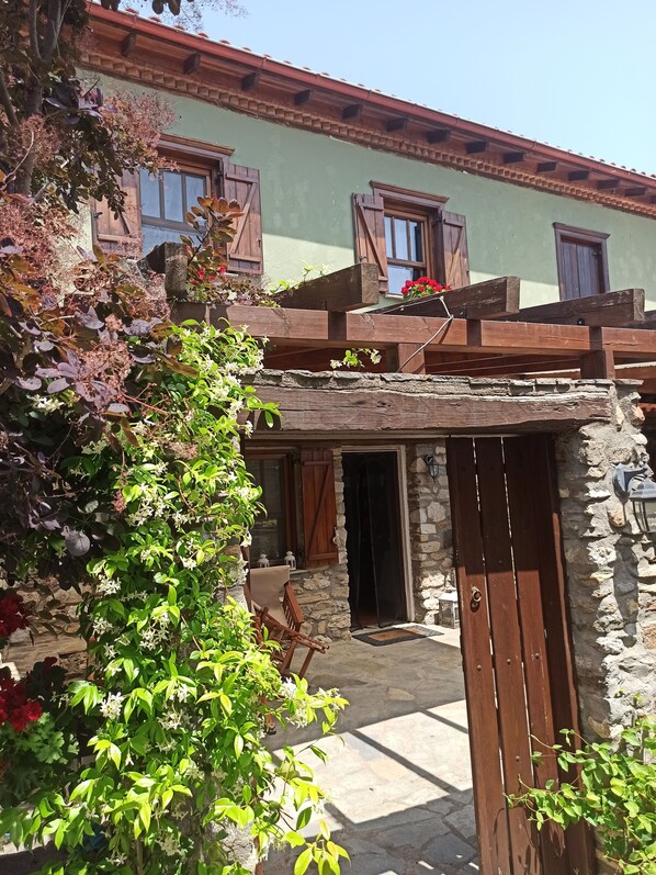 A rustic building with a stone facade, wooden shutters, and a wooden pergola with flowers. - Luxury Traditional Stone House in Vrasna (Vrasna)