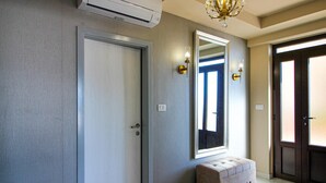 Un pasillo con una puerta cerrada, un espejo y un banco.