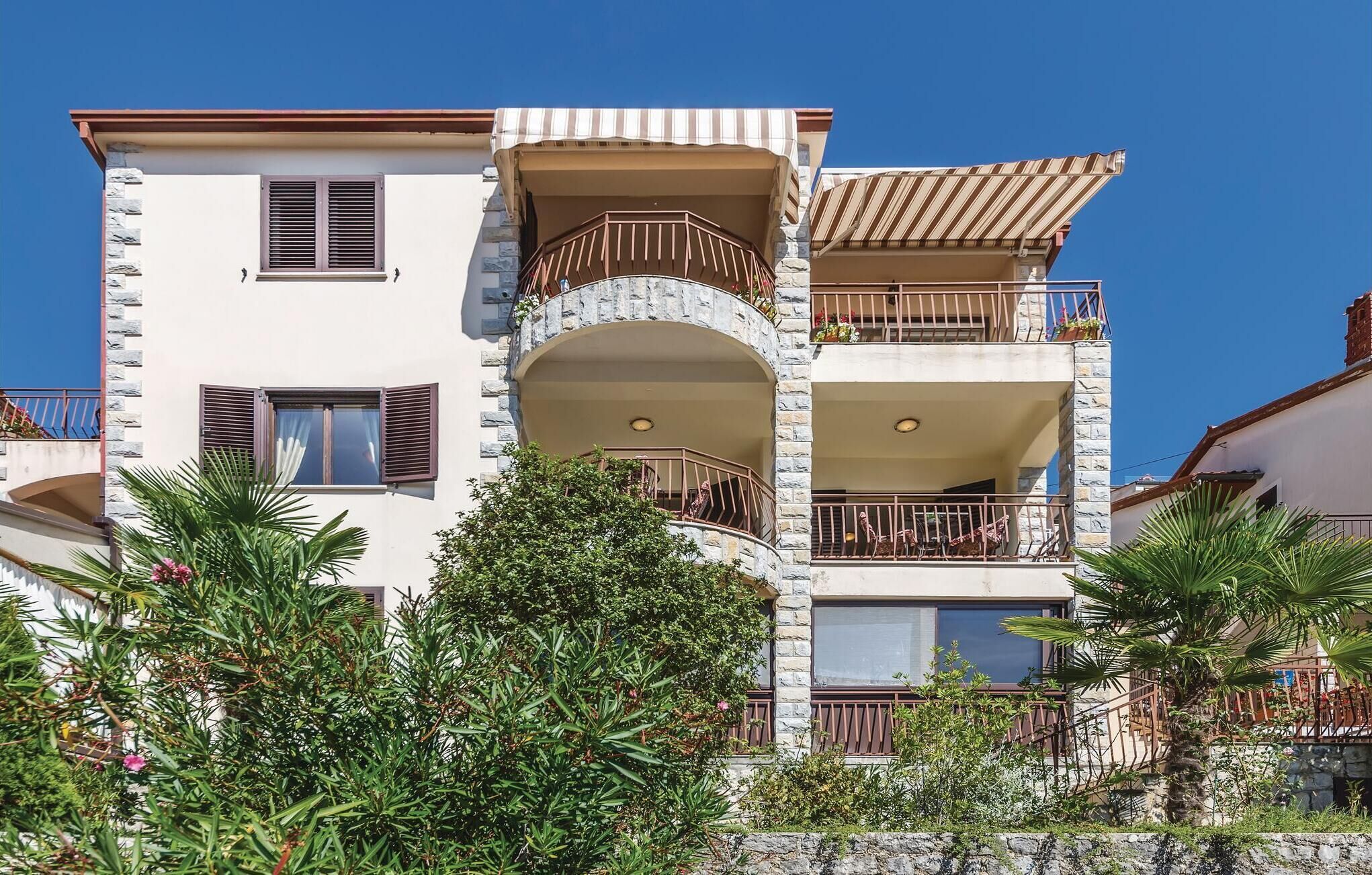 A multi-story building with balconies, stone facade, and a clear blue sky.