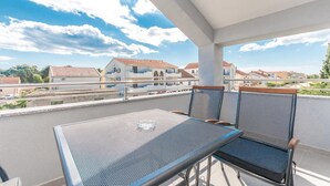 A balcony with a table and chairs, overlooking a residential area with houses and a road. - Lovely apartment in Biograd with WiFi (Biograd)