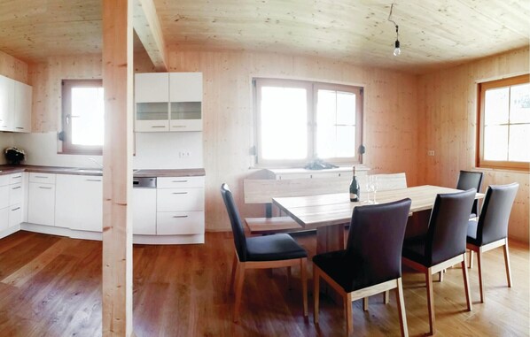 A wooden cabin with a kitchen, dining area, and large windows.