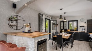 A modern kitchen with a wooden island, black chairs, and a stone fireplace. - Stunning home in Opatija with sauna (Opatija)