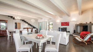 A spacious living area with a dining table, white sofas, and a fireplace. - Lovely home in Montecastrilli (Montecastrilli)