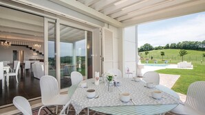 A dining area with a table set for four, surrounded by white chairs, overlooking a pool and a grassy landscape. - Lovely home in Montecastrilli (Montecastrilli)