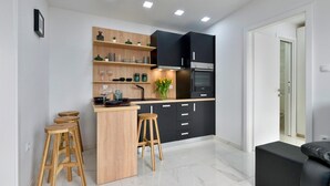 Une cuisine moderne avec des meubles noirs, des tabourets en bois et un plan de travail en marbre.