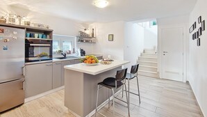 Une cuisine moderne dotée d’un îlot central, d’appareils électroménagers en acier inoxydable et d’un plancher en bois.