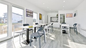 Un intérieur moderne comprenant un coin repas, une cuisine et de grandes fenêtres.
