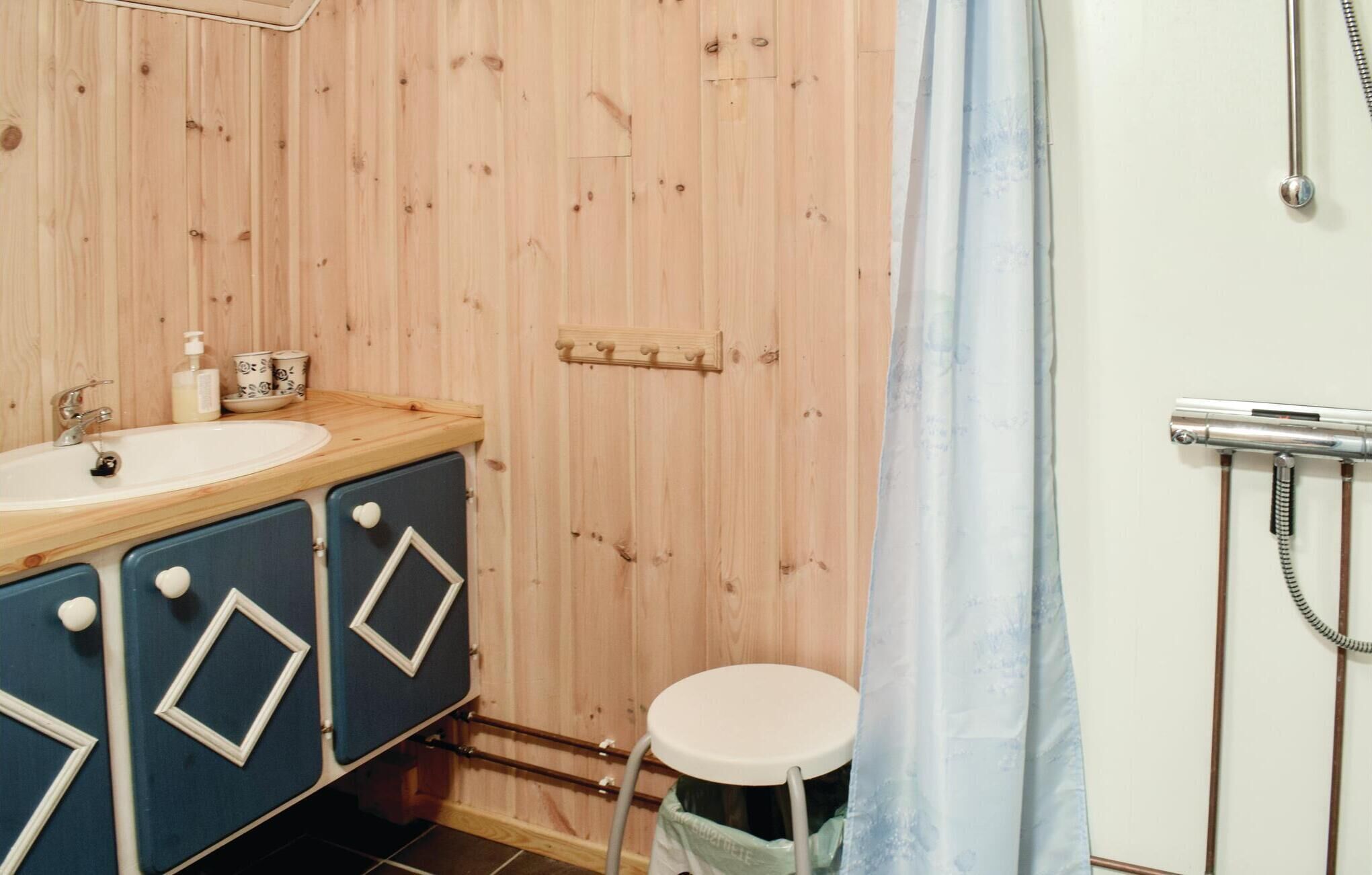 Une salle de bain avec un mur en bois, un lavabo, un miroir, une douche et des toilettes.